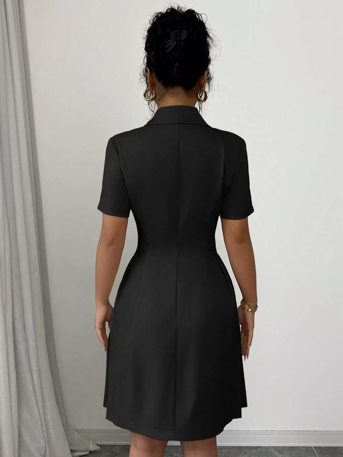 Black double-breasted pleated blazer mini dress, back view.