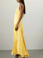 Yellow pleated halter-neck maxi dress, side view.