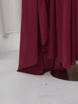 Burgundy ruched halter cape maxi dress, hem detail.