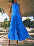 Blue pleated halter-neck maxi dress, side view.