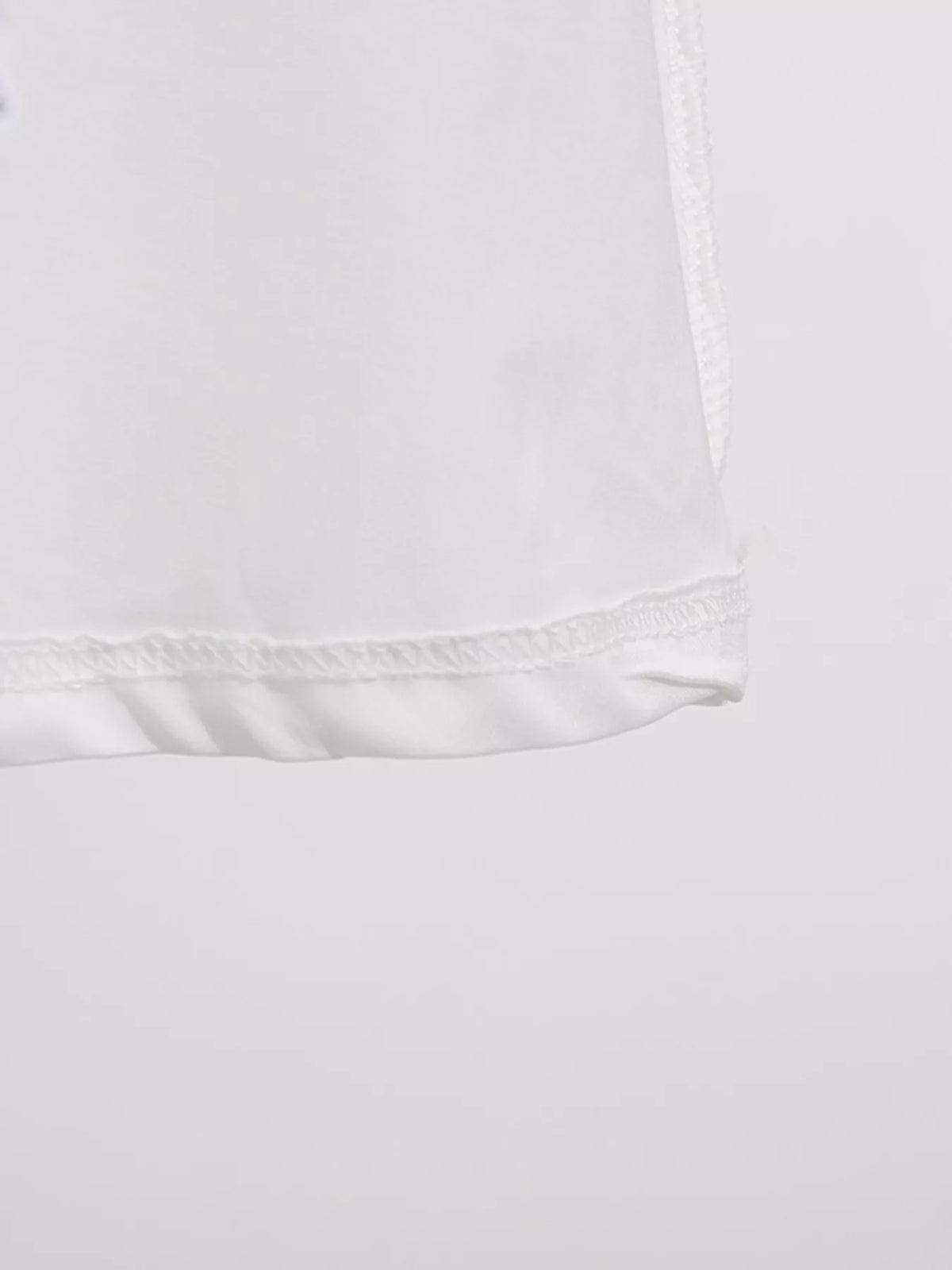 White sleeveless floral appliqué midi dress, hem detail.