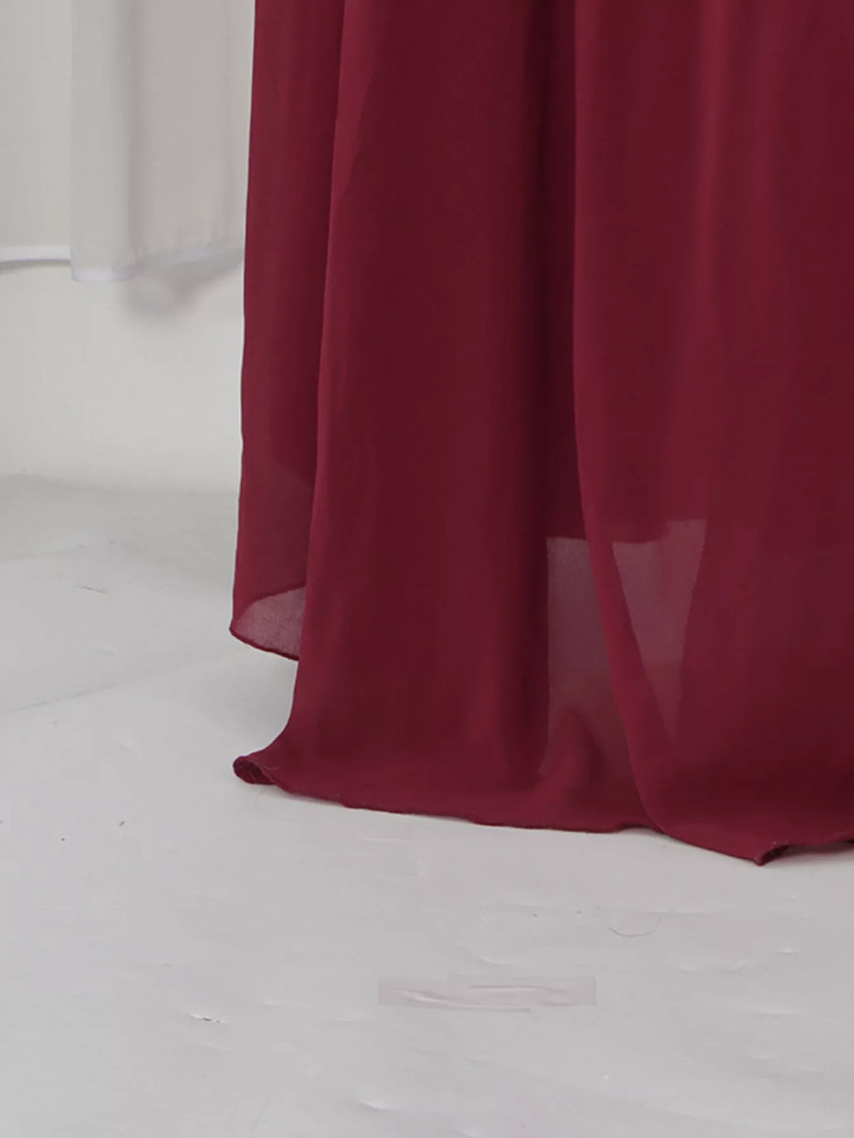 Burgundy ruched halter cape maxi dress, hem detail.