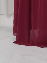 Burgundy ruched halter cape maxi dress, hem detail.